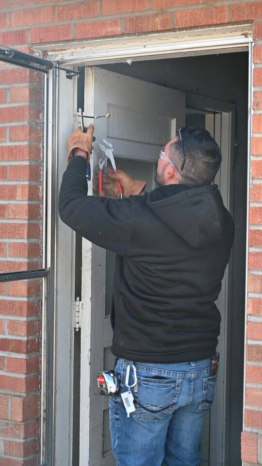 A Central New Mexico Housing Corporation employee installs weather stripping to air seal a door.